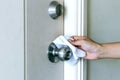 Cleaning door knob, hand use alcohol clean pad wiping door knob before entering the room of building for disinfect virus bacteria