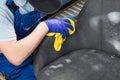 After cleaning the drapery of the chair with active foam, a hand in a protective glove, erases the excess