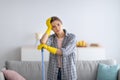 Cleaning is so dull. Bored millennial woman in rubber gloves leaning on mop, tired of household chores Royalty Free Stock Photo