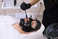 Spa therapy for men receiving facial black mask.