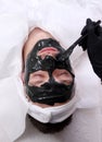 Spa therapy for men receiving facial black mask.
