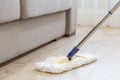 Cleaning floor with white mop near sofa Royalty Free Stock Photo