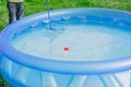 Cleaning of garden swimming pool . Boy tries to cach red ball with Skimmer net Royalty Free Stock Photo