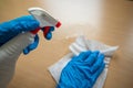 Cleaning home table sanitizing office table surface with disinfectant spray bottle washing surfaces with towel and gloves. COVID- Royalty Free Stock Photo