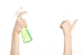 Cleaning the house and cleaner theme: man's hand holding a green spray bottle for cleaning isolated on a white background