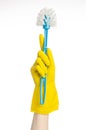 Cleaning the house and cleaning the toilet: human hand holding a blue toilet brush in yellow protective gloves isolated on a white Royalty Free Stock Photo