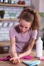 Disquieted light-haired girl leaning on kitchen table and inspecting