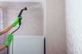 Cleaning in the house. A girl in brightly green gloves cleans the kitchen range hood in the apartment with a steam cleaner. we Royalty Free Stock Photo