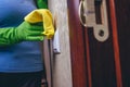 Cleaning in the house. A girl in green gloves wipes the electricity switch with a yellow cloth. cleaning from dust. Cleaning of