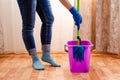 Cleaning the house with a lilac bucket, blue gloves, a mop and cleaning lady`s feet. Home cleaning concept