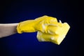 Cleaning the house and sanitation topic: Hand holding a yellow sponge wet with foam on a dark blue background in studio Royalty Free Stock Photo