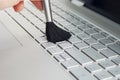 Cleaning keyboard and caring computer. cleaning the keyboard of the modern gray ultrabook transformer with a black brush from dust Royalty Free Stock Photo