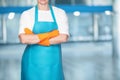 A cleaning lady in aprons with her arms crossed stands