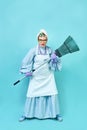 Cleaning Lady Fun. Elderly funny housewife fooling around with a broom. Full body isolated blue