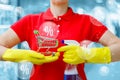 Cleaning lady holds a shopping basket and spray in her hands against the background of percents flying in a bubbles