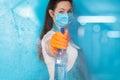 Cleaning lady in a mask disinfects a blue background Royalty Free Stock Photo