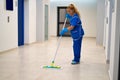 A cleaning lady mops the floor in an office building