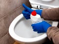 The cleaning lady near the toilet with cleaning agent shows the ok sign with her hand. The toilet is clean