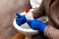 The cleaning lady near the toilet with cleaning agent shows the ok sign with her hand. The toilet is clean Royalty Free Stock Photo