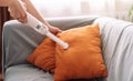 Cleaning lady vacuuming orange pillows on the sofa with a handheld vacuum cleaner Royalty Free Stock Photo