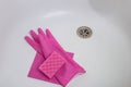 Cleaning limescale in the bathroom. Concept of cleaning dirty washbasin with limescale stains in the bathroom. Pink gloves and