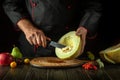 Cleaning the melon on the kitchen table by the hands of the chef before slicing. Fruit diet concept on dark background. Asian Royalty Free Stock Photo