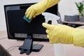 Cleaning the office, a janitor in yellow gloves wipes monitor and computer equipment with a rag Royalty Free Stock Photo