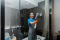 Cleaning online service. yong woman housekeeper cleaning bathroom mirror with cloth. House cleaning service concept Royalty Free Stock Photo