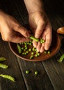 Cleaning peas after harvest. Close-up male hands are peeling peas into a plate. Vegetarian food preparation