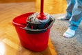 Cleaning person dips mop into bucket. Close-up of the legs, top view. Chores and washing