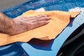 Cleaning or polishing of a blue car with microfiber cloth. Manual car washing service.