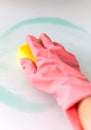 Cleaning process. Hand in a pink glove that washes the white table with a yellow sponge Royalty Free Stock Photo