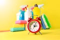 Cleaning service background with household chemicals and red alarm clock. Saving time in house cleaning concept Royalty Free Stock Photo