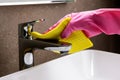 cleaning service and chores. hand with rubber glove and sponge cleans the bathroom sink chrome faucet Royalty Free Stock Photo