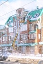 The cleaning service cleans the snow from the roof of the house.