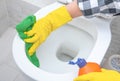 Close up hand with detergent cleaning toilet. Cleaning service. Hands wearing yellow protect glove using liquid cleaning solution Royalty Free Stock Photo