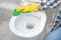 Cleaning service. close up hands wearing yellow protect glove using green microfiber cloth cleaning flush toilet, disinfection and Royalty Free Stock Photo