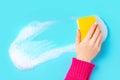 Female hand holding sponge with a foamy detergent over a blue surface Royalty Free Stock Photo