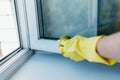 Cleaning service with gloves washes the window frame with a rag in the summer Royalty Free Stock Photo