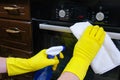 Cleaning service in the kitchen. Hands in gloves, washing and cleaning a gas stove in the kitchen with a rag Royalty Free Stock Photo