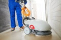 Worker with machine cleaning floor in residence hall