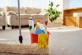 Cleaning set for different surfaces in orange bucket and mop on floor in living room, copy space. Cleaning service concept. Royalty Free Stock Photo