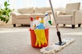 Cleaning set for different surfaces in orange bucket and mop on floor in living room, copy space. Cleaning service concept. Royalty Free Stock Photo