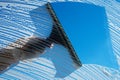 Cleaning soapy windows with squeegee against sunny blue sky. Spring house cleaning concept. Copy space Royalty Free Stock Photo