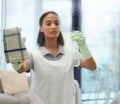 Cleaning spray, woman and home with cloth and living room task with washing glass. Young female person, maid and apron