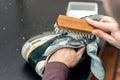 Cleaning suede sneakers. A worker in a shoe workshop cleans a pile of shoes Royalty Free Stock Photo