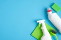 Cleaning supplies on blue background. Top view cleaner spray bottle, green rag, sponge, detergent, brush, rubber gloves. House Royalty Free Stock Photo