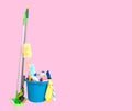 Cleaning supplies in blue bucket on pastel pink background Royalty Free Stock Photo