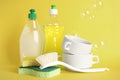 Cleaning supplies for dish washing and soap bubbles on yellow background Royalty Free Stock Photo