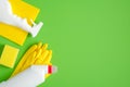 Cleaning supplies on green background. Top view cleaner spray bottle, rag, sponge, detergent, yellow rubber gloves. House cleaning